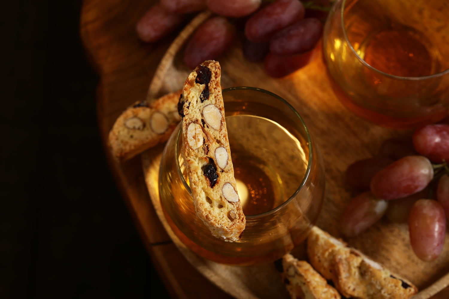 glass of dessert wine with biscotti and grapes on a table