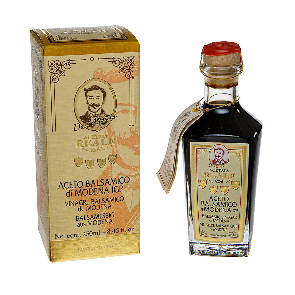 Een rechthoekig doosje en een langwerpig flesje balsamico azijn. Op het etiket staat Ecetaia Reale 1896 Aceto Balsamico di Modena IGP